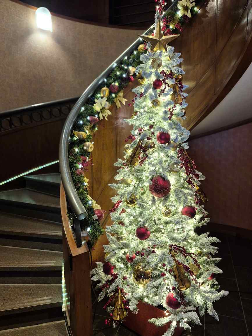 Sapin de Noël illuminé rouge et or dans un escalier corporatif